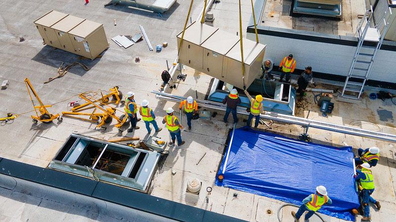 Aerial view of a worksite showing many construction workers on a roof